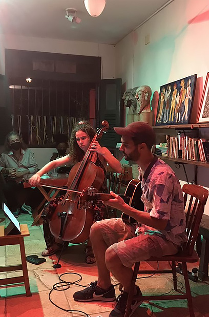 homem sentado em banco tocando violão